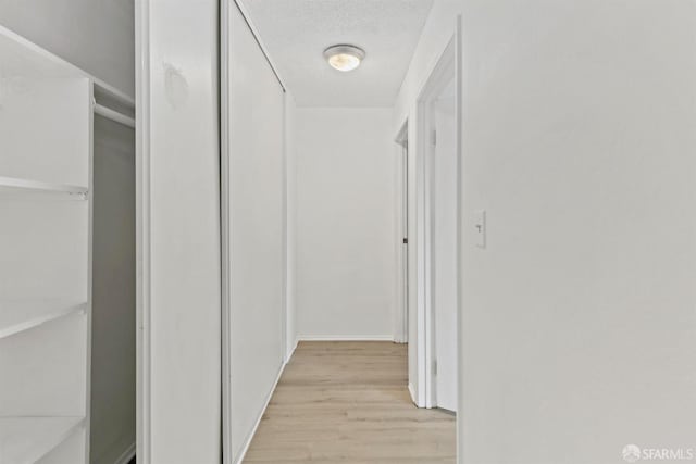 hall featuring a textured ceiling and light wood finished floors