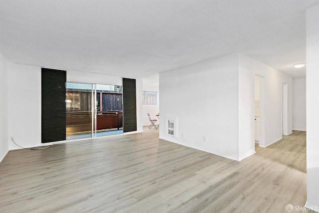 unfurnished room with light wood-style flooring and a textured ceiling