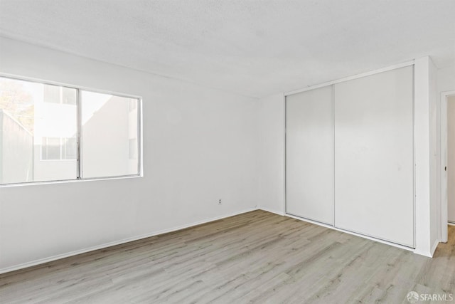 unfurnished bedroom featuring light wood-style floors and a closet