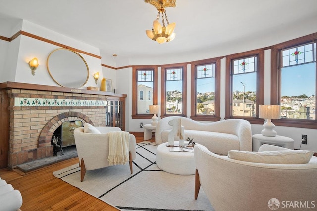 living room featuring a chandelier, light hardwood / wood-style floors, and a brick fireplace