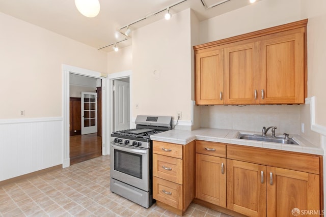 4632 18th St, San Francisco, CA 94114 - kitchen with stainless steel gas range oven, rail lighting, tile countertops, and a wainscoted wall
