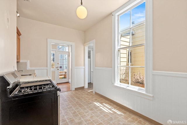 4632 18th St, San Francisco, CA 94114 - kitchen with stainless steel gas range oven, wainscoting, light floors, and decorative light fixtures