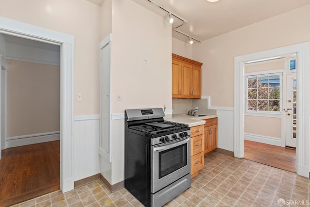 4632 18th St, San Francisco, CA 94114 - kitchen with stainless steel gas range, light countertops, wainscoting, light wood-style floors, and rail lighting