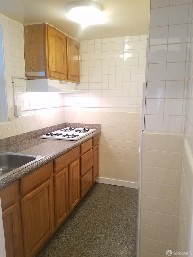 kitchen featuring sink, tile walls, and white gas stovetop