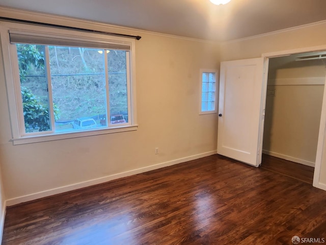 unfurnished bedroom with multiple windows, a closet, dark wood-type flooring, and crown molding