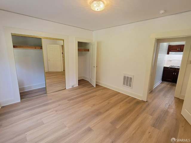 unfurnished bedroom with two closets and light hardwood / wood-style floors