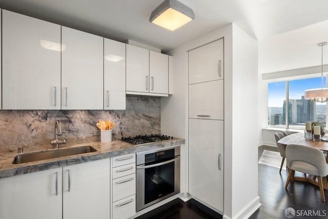 kitchen with a city view, a sink, white cabinetry, appliances with stainless steel finishes, and backsplash