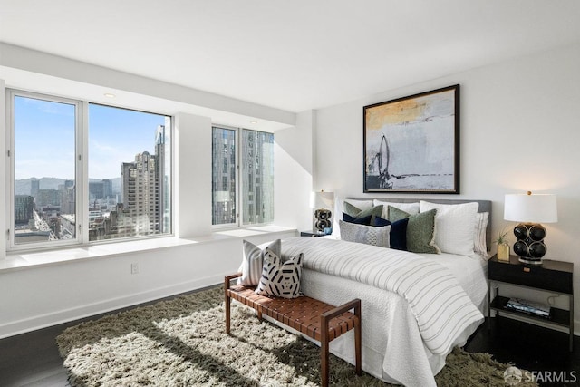 bedroom with a city view, baseboards, and wood finished floors