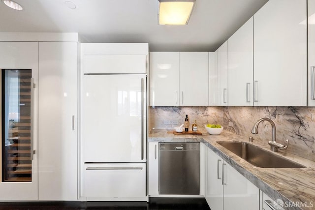 kitchen with paneled built in fridge, white cabinets, dishwasher, backsplash, and a sink