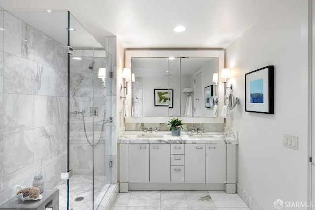 bathroom featuring double vanity, marble finish floor, a shower stall, and a sink