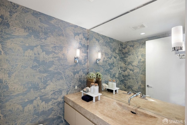 bathroom featuring visible vents, vanity, and wallpapered walls