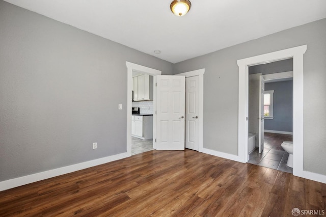 unfurnished bedroom with light wood-style floors, baseboards, and connected bathroom