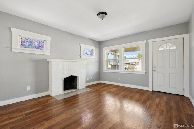 unfurnished living room with baseboards, a tile fireplace, and hardwood / wood-style floors