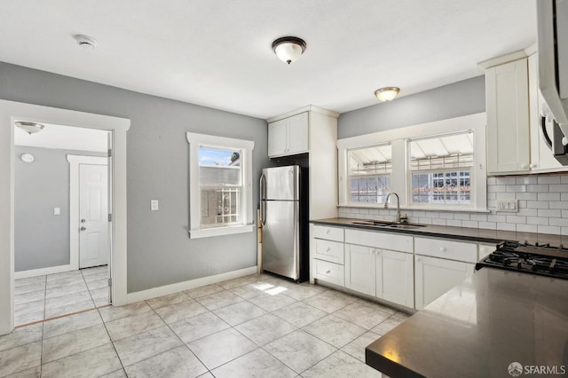 kitchen featuring a sink, dark countertops, decorative backsplash, and freestanding refrigerator