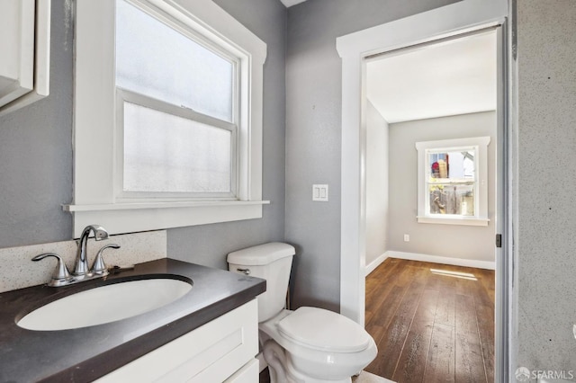 bathroom featuring vanity, a healthy amount of sunlight, hardwood / wood-style floors, and toilet