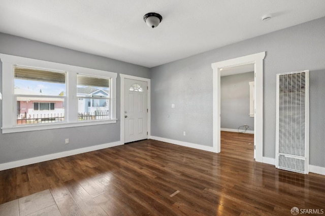 foyer entrance featuring baseboards, wood finished floors, and a heating unit
