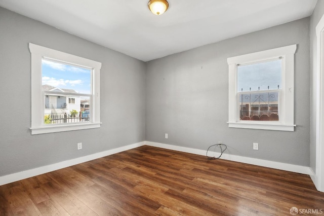 empty room with plenty of natural light, baseboards, and wood finished floors