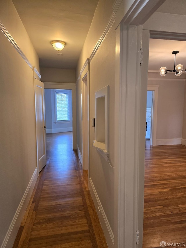 corridor featuring dark wood-type flooring and an inviting chandelier