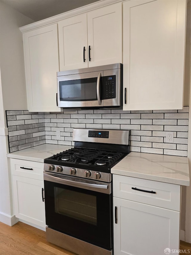 kitchen with white cabinetry, stainless steel appliances, and backsplash