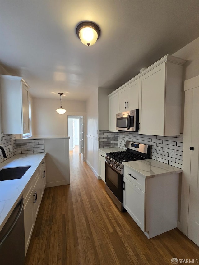 kitchen with sink, hanging light fixtures, white cabinetry, stainless steel appliances, and dark wood-type flooring