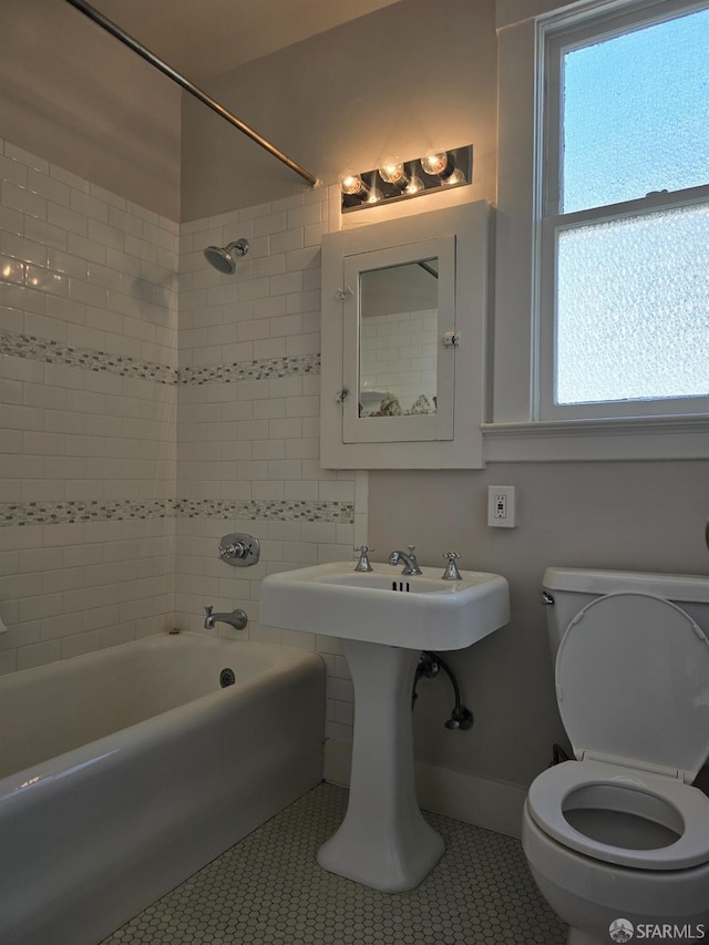 bathroom with toilet, tiled shower / bath, and tile patterned flooring