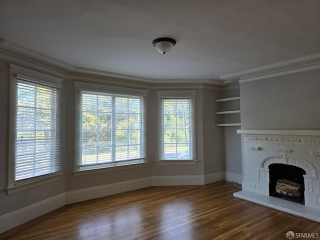 unfurnished living room featuring hardwood / wood-style flooring, a healthy amount of sunlight, crown molding, and a fireplace