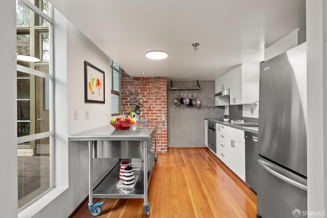 461 2nd St Unit C135, San Francisco, CA 94107 - kitchen featuring appliances with stainless steel finishes, white cabinets, light wood finished floors, a sink, and under cabinet range hood