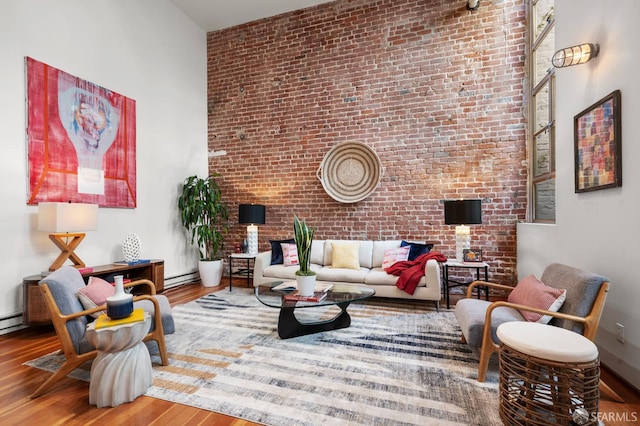 461 2nd St Unit C135, San Francisco, CA 94107 - living area featuring a towering ceiling, brick wall, wood finished floors, and a baseboard radiator