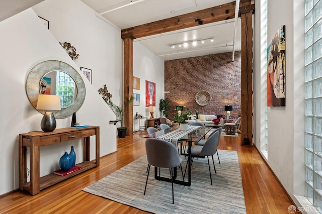 461 2nd St Unit C135, San Francisco, CA 94107 - dining space featuring wood finished floors, brick wall, a high ceiling, track lighting, and beamed ceiling