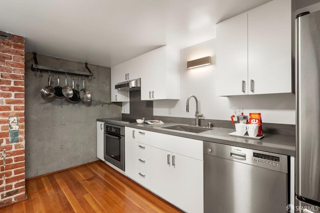 461 2nd St Unit C135, San Francisco, CA 94107 - kitchen with stainless steel appliances, a sink, wood finished floors, dark countertops, and under cabinet range hood