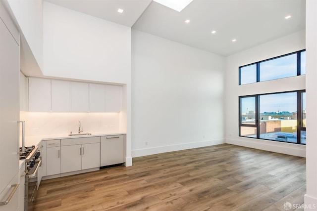 bar featuring a high ceiling, a sink, high end range, and light wood-style floors