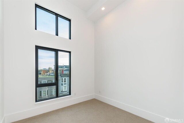 spare room with recessed lighting, a healthy amount of sunlight, light colored carpet, and baseboards