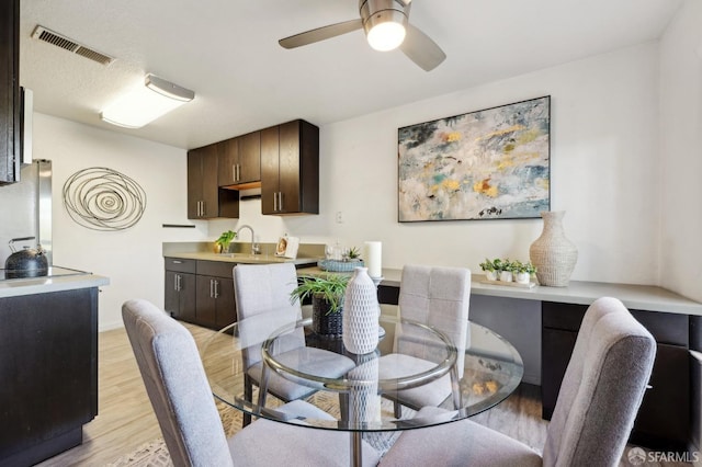 dining room with sink, ceiling fan, and light hardwood / wood-style flooring