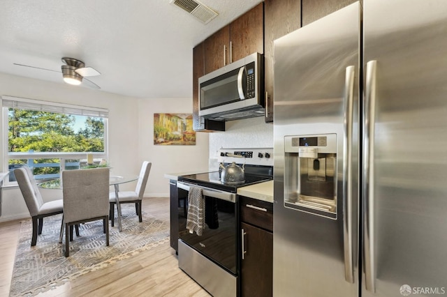 kitchen with dark brown cabinets, appliances with stainless steel finishes, ceiling fan, and light hardwood / wood-style floors