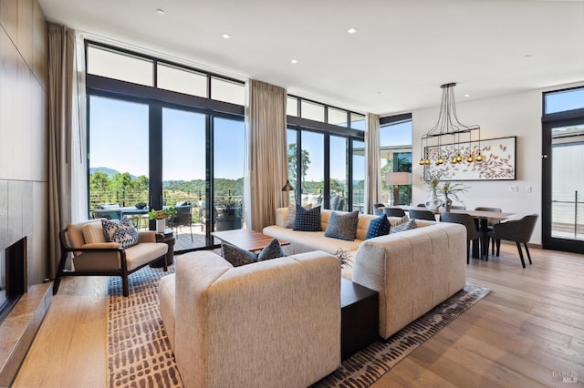 living area with a glass covered fireplace, light wood finished floors, and a wall of windows