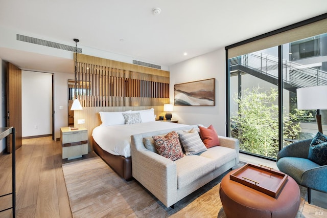 bedroom featuring recessed lighting, light wood-type flooring, and a wall of windows
