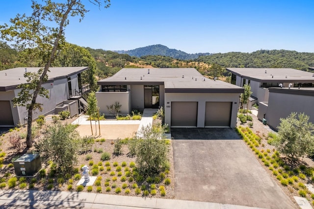 view of front of home featuring aphalt driveway, stucco siding, a mountain view, and an attached garage
