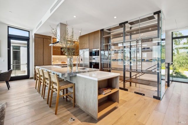kitchen featuring light wood finished floors, modern cabinets, open shelves, and brown cabinets