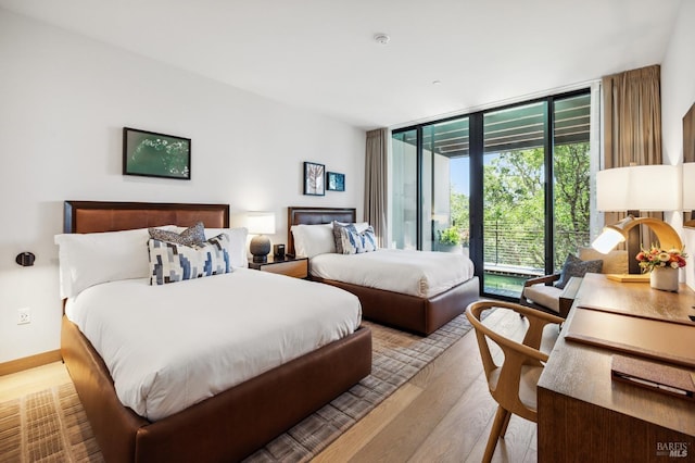 bedroom with access to exterior, wood finished floors, and expansive windows