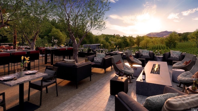 patio terrace at dusk featuring a mountain view and an outdoor living space with a fire pit
