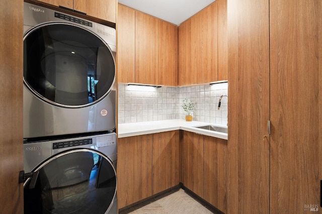 washroom featuring stacked washer and clothes dryer, a sink, and cabinet space