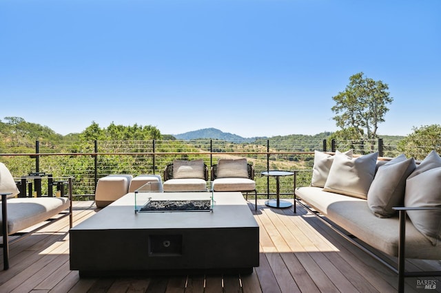 deck featuring a mountain view and an outdoor living space with a fire pit