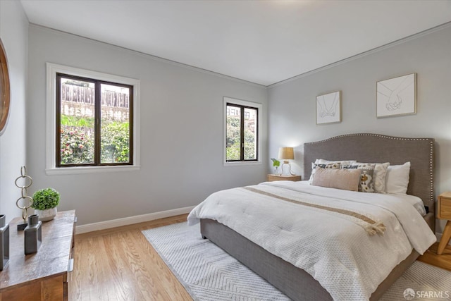 bedroom with ornamental molding and light hardwood / wood-style flooring