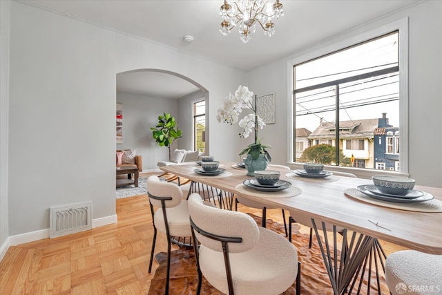 dining area with ornamental molding, a chandelier, and light parquet floors