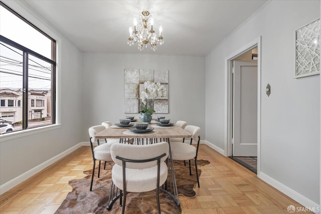 dining area with light parquet flooring, plenty of natural light, ornamental molding, and a chandelier