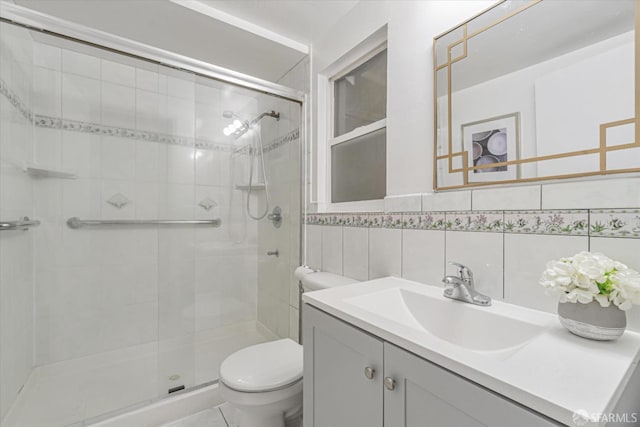 bathroom featuring vanity, a shower with door, tile walls, and toilet