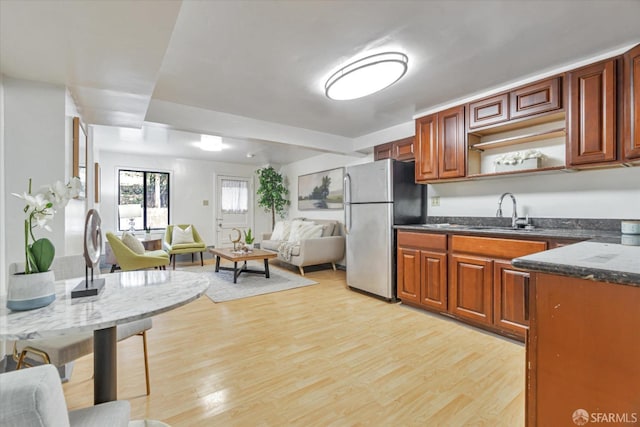 kitchen with stainless steel fridge, sink, and light hardwood / wood-style flooring