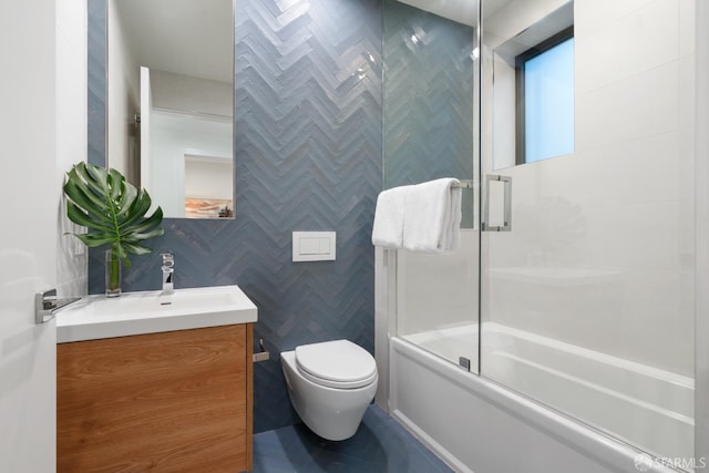 full bathroom with toilet, vanity, shower / bath combination with glass door, and tile walls