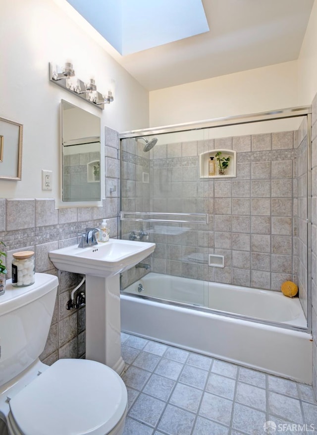 636 Edgemar Ave, Pacifica, CA 94044 - bathroom featuring tile walls, combined bath / shower with glass door, a skylight, and wainscoting