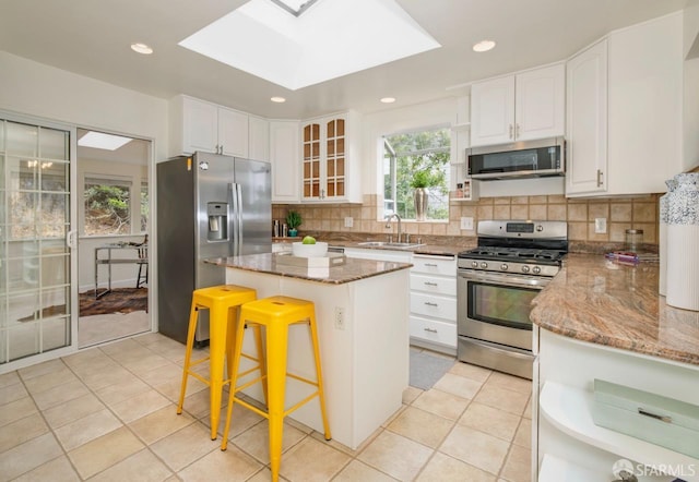 636 Edgemar Ave, Pacifica, CA 94044 - kitchen with appliances with stainless steel finishes, dark stone counters, white cabinetry, a center island, and recessed lighting